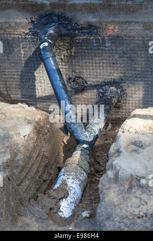 Poli cloruro di vinile (PVC) tubi essendo installati per la raccolta di acqua piovana sistema presso la casa nuova costruzione. Foto Stock