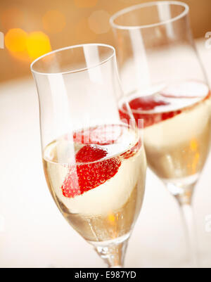 Primo piano di un elegante champagne flutes riempiti con refrigerate frizzante e di un galleggiante fragola per celebrare una serata romantica insieme Foto Stock