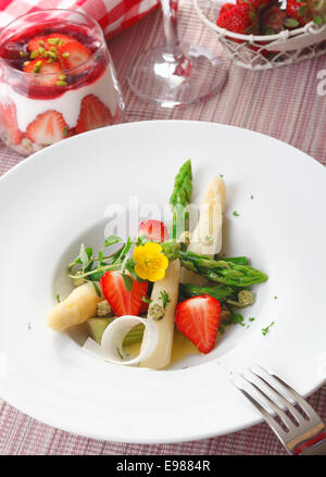 Insalata di fresco a dadini di punte di asparagi e fragole servite in un semplice piatto bianco. Elevato angolo di visualizzazione. Foto Stock