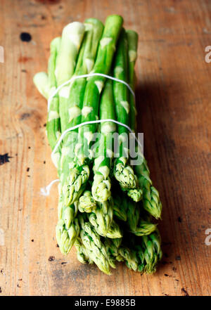 Mazzetto di freschi Asparagi verdi spears legati con spago su una tavola in legno rustico top Foto Stock