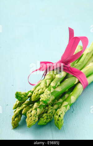 Mazzetto di fresca giovani punte di asparagi legato decorativa con un nastro rosa Foto Stock