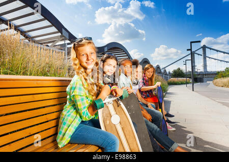 Kids sedersi sulla panchina in estate con skateboard Foto Stock