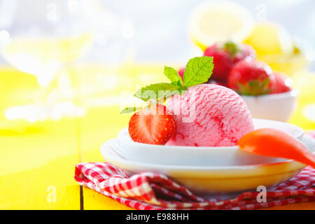 Tropical fragola gelato servito con fresche fragole mature in una impostazione di piano portapaziente su una vacanza estiva Foto Stock