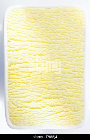 Primo piano verticale texture di sfondo di una vasca del sorbetto al limone o gelato alla vaniglia con un ripple di shadowing che corre attraverso il centro Foto Stock