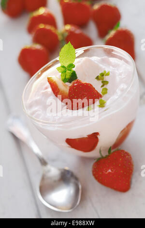 Ripe rosso succose fragole e fresco di yogurt o panna montata in una ciotola di vetro per una rinfrescante dessert prodotti lattiero-caseari Foto Stock