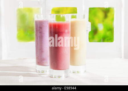 Varietà di frutti sani e freschi t frullati in bicchieri realizzati a partire da una miscela di crema di yogurt e frutta liquidised Foto Stock