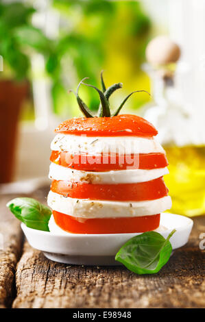 Formaggio e pomodoro tower con strati alternati di freschi maturi rosso pomodoro e formaggio servita su una tavola in legno rustico Foto Stock