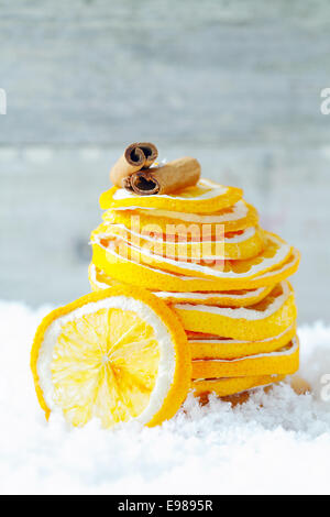 Una pila di essiccato fettine di arancia e cannella sulla neve per la stagionatura il vostro drink caldi e dessert durante un inverno freddo Foto Stock