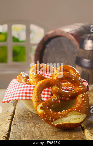 Croccante salato dorati pretzel è servita come uno snack salato in un pub o un ristorante con una vecchia botte di vino visibile dietro Foto Stock