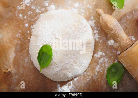 Pasta di pane fresco con un mattarello su una superficie di legno pronto per essere implementato per una base per pizza o pasticceria Foto Stock