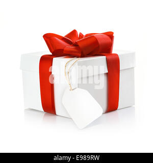 Natale regalo a sorpresa con tag vuoto e una decorazione a nastro rosso e la prua su un bianco di sfondo per studio Foto Stock