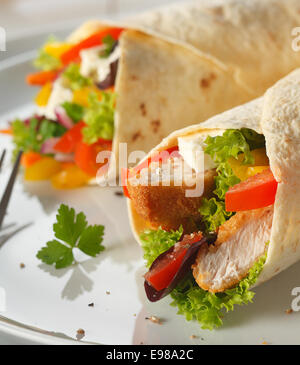 Deliziosi pancake vegetariano avvolge riempito con il formaggio feta, insalata e croccanti bocconcini di pane, closeup vista su una piastra Foto Stock