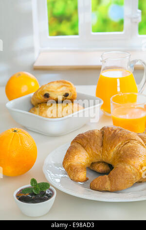 Pane appena sfornato golden croissant serviti con marmellata e succo d'arancia fresco per una sana prima colazione continentale Foto Stock