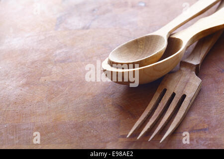 In legno fatti a mano gli utensili da cucina con una forchetta e cucchiai in due dimensioni giacente su di una superficie di legno con copyspace Foto Stock