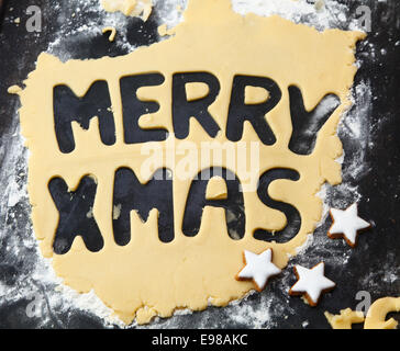 Testo Buon Natale tagliati in impasto arrotolato su una superficie farinosa con stella biscotti per Natale divertente la cottura Foto Stock