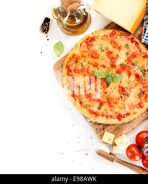 Vista dall'alto di una pizza Margherita vicino agli ingredienti come pomodori, olio di oliva, formaggio, basilico, pepe e utensili per la cucina Foto Stock