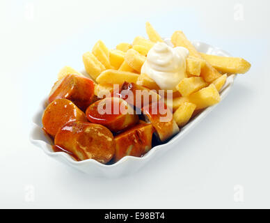 Currywurst servita in un piatto di portata con golden fritte patatine e rabboccato con maionese, su bianco Foto Stock