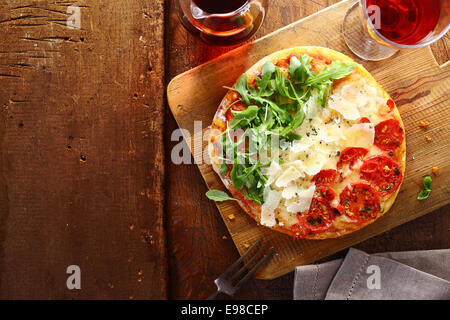 Italiano patriottica pizza tricolore con strisce di colore rosso, bianco e verde con i colori della bandiera nazionale formato da pomodoro, formaggio fresco e rucola utilizzato per il topping su un tavolo di legno con copyspace Foto Stock