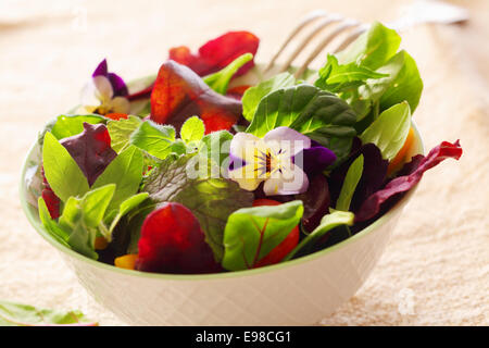 Erba fresca insalata con foglie verdi e i Nasturzi fiori servita in un bianco vaso in ceramica Foto Stock