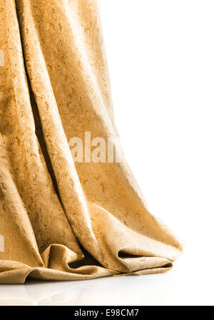 Elegante damasco oro o brocade appesa al pavimento in morbidi tendaggi lussuosi contro uno sfondo bianco con copyspace Foto Stock