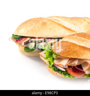 Due fresca baguette croccanti con ripieno gustoso, uno con spicchi di fichi, spinaci e formaggio blu e gli altri con elaborati di pollo tagliato a fette e insalata su bianco in formato quadrato Foto Stock