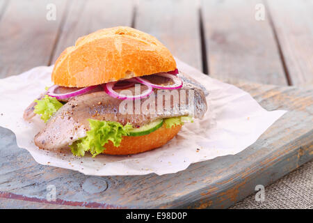 Hamburger di pesce con un pane appena sfornato crusty bun, filetto di pesce, cipolla e lattuga servita su un rustico di legno Foto Stock