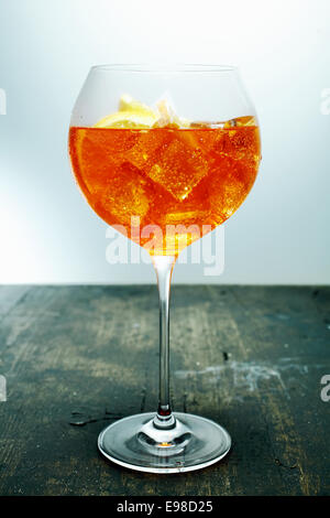 Refrigerate tropical aperol, rum e orange cocktail in un elegante bicchiere di vino in piedi su un banco di legno in un bar o club Foto Stock