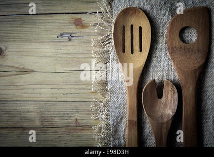 Vecchi rustici di legno utensili di cottura su un vecchio pezzo di tela su una superficie in legno con copyspace Foto Stock