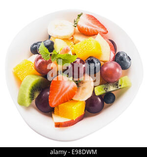 Vicino la vista dal di sopra della frutta fresca tropicale insalata in una ciotola con dadolata di kiwi e mela, arancio, uva, banana, fragole e mirtilli, isolato su bianco Foto Stock