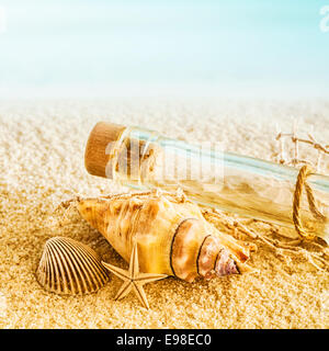 Natura morta marina con una arricciatura, stelle marine e conchiglia giacente sulla sabbia dorata su una spiaggia tropicale a fianco di un tappo smerigliato vuoto bottiglia di vetro chiaro lavato fino in riva al mare dalle maree Foto Stock