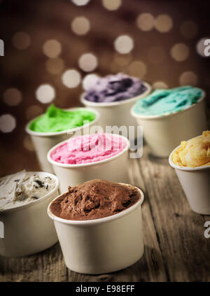 Delizioso assortimento di parte del gelato in singoli vasetti di plastica in più colori e sapori con un frizzante bokeh di luci festive Foto Stock