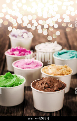 Coloratissimo gelato italiano in diversi colori e sapori in singoli contenitori per una occasione di festa con un batter bokeh di luci di partito Foto Stock