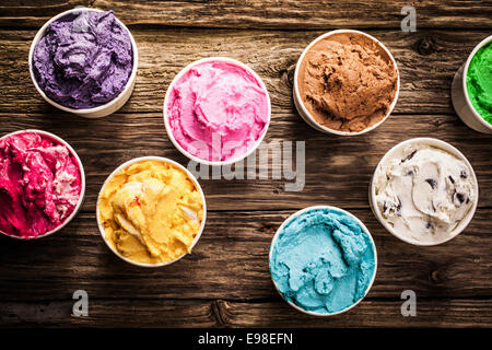 Selezione di sapori gourmet del gelato italiano in colori vibranti servita in singoli vasetti di plastica su un vecchio rustico tavolo in legno in una gelateria, vista aerea Foto Stock