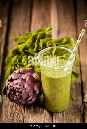 Vegetariano sano carciofo e lattuga smoothie con ingredienti freschi in un vecchio rustico in legno tavolo da cucina Foto Stock