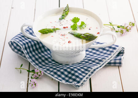 Crema di zuppa di asparagi freschi con punte di asparagi verdi e conditi con spezie servito in una ciotola su una blu e bianco panno controllati Foto Stock