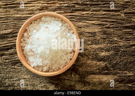 Piccola ciotola di legno di Himalayan rock salt dalle miniere in Pakistan su un weathered texture di sfondo di legno, vista aerea Foto Stock