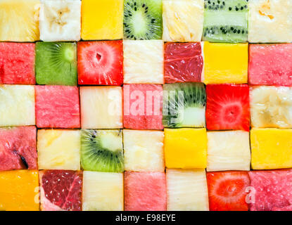 Perfetta configurazione di sfondo e texture di colorati a dadini fresca frutta tropicale cubi disposti in un disegno geometrico con melone, anguria, banana, ananas, fragole, kiwi e pompelmo Foto Stock