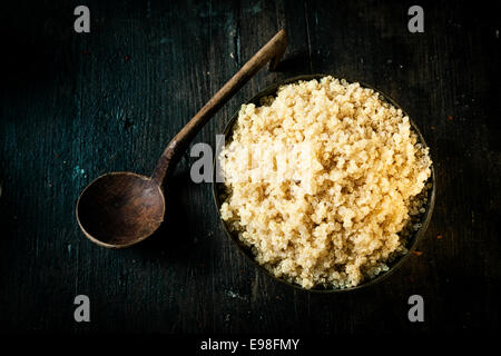 Vista aerea di una tazza di delizioso quinoa sani realizzati dai semi della pianta goosefoot e classificato come superfood per il suo alto contenuto di proteine e di valore nutritivo su sfondo scuro Foto Stock