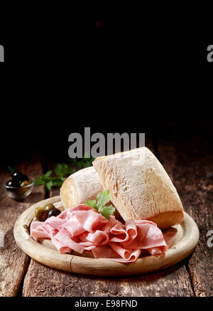 Vulcanizzati a fette sottili di prosciutto tedesco con crosta di rulli per un paese il pranzo è servito su un tagliere di legno con copyspace, formato verticale Foto Stock