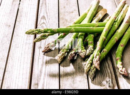 Bundle di fresco verde i turioni degli asparagi, suggerimenti o lance sul display nel mercato degli agricoltori che giace su di una tavola in legno rustico al sole con copyspace Foto Stock