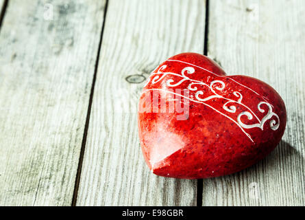 Cuore rosso pietra sagomata sulla superficie di legno Foto Stock