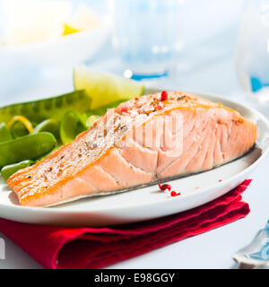 Sana rosa gourmet bistecca di salmone ricco di omega 3 servita con fresco verde taccole piselli e limone, vicino che mostra la consistenza del pesce Foto Stock