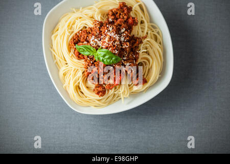 Ciotola di delcious italiano gli spaghetti conditi con un ricco di pomodoro e carne salsa bolognaide condito con basilico e parmigiano, vista aerea Foto Stock