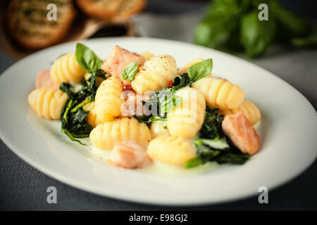 Italian gnocchi di pasta, o gnocchi con salmone alla griglia e pezzi di basilico fresco su una targhetta ovale Foto Stock