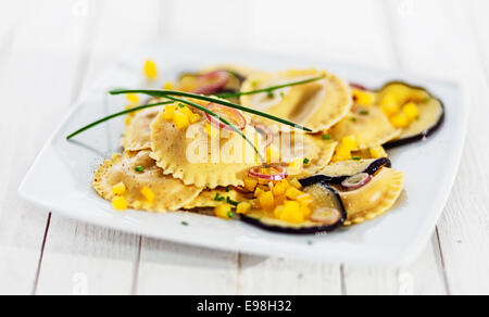 La deliziosa cucina italiana ravioli di pasta con le fette di carne saltata o Melanzane Arrosto, melanzana o brinjal conditi con formaggio e erba cipollina fresca, closeup vista con dof poco profondo Foto Stock