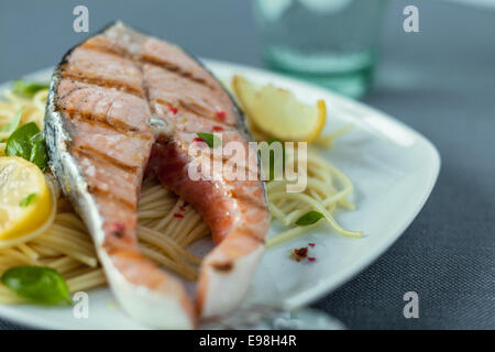 Gourmet salmone alla griglia bistecche servite su un letto di pasta italiana tagliatelle con basilico e limone Foto Stock