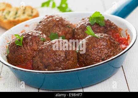 Padella con cinque salato polpette di italiano in piccante salsa di pomodoro guarnita con basilico fresco, closeup basso angolo di visione Foto Stock