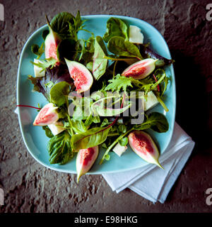 Macro fichi appetitosi e insalata selvatica su sfondo rustico. Buona per gli appassionati di verdure Foto Stock