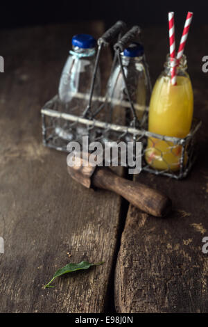 Bottiglie di succhi di frutta nel vassoio sul tavolo di legno. Foto Stock