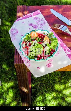 Outdoor appetitosi Insalata estiva con feta su un tavolo di legno. Forchetta e coltello sul lato. Foto Stock